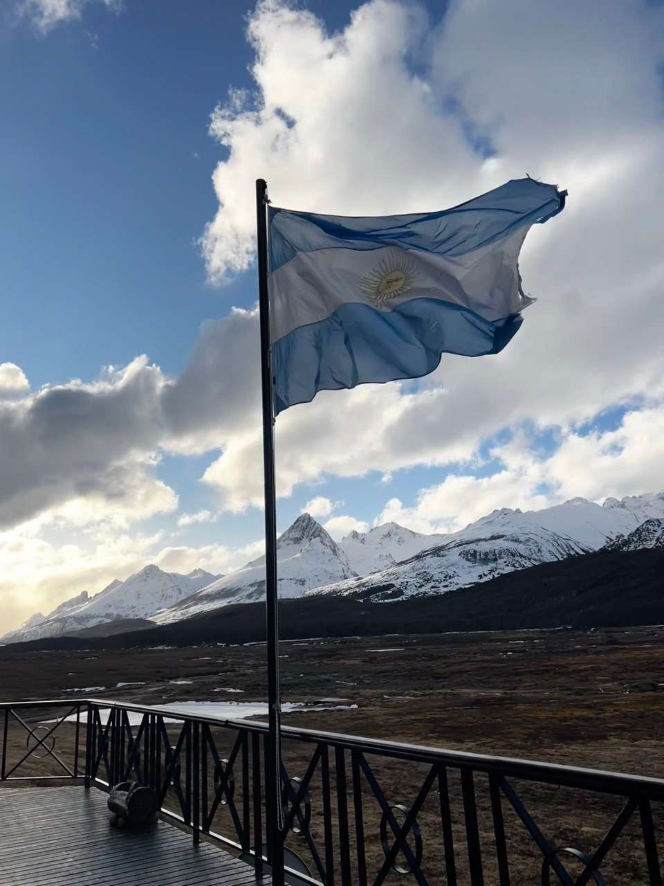 Argentine flag waving in Ushuaia with snowy Andes behind